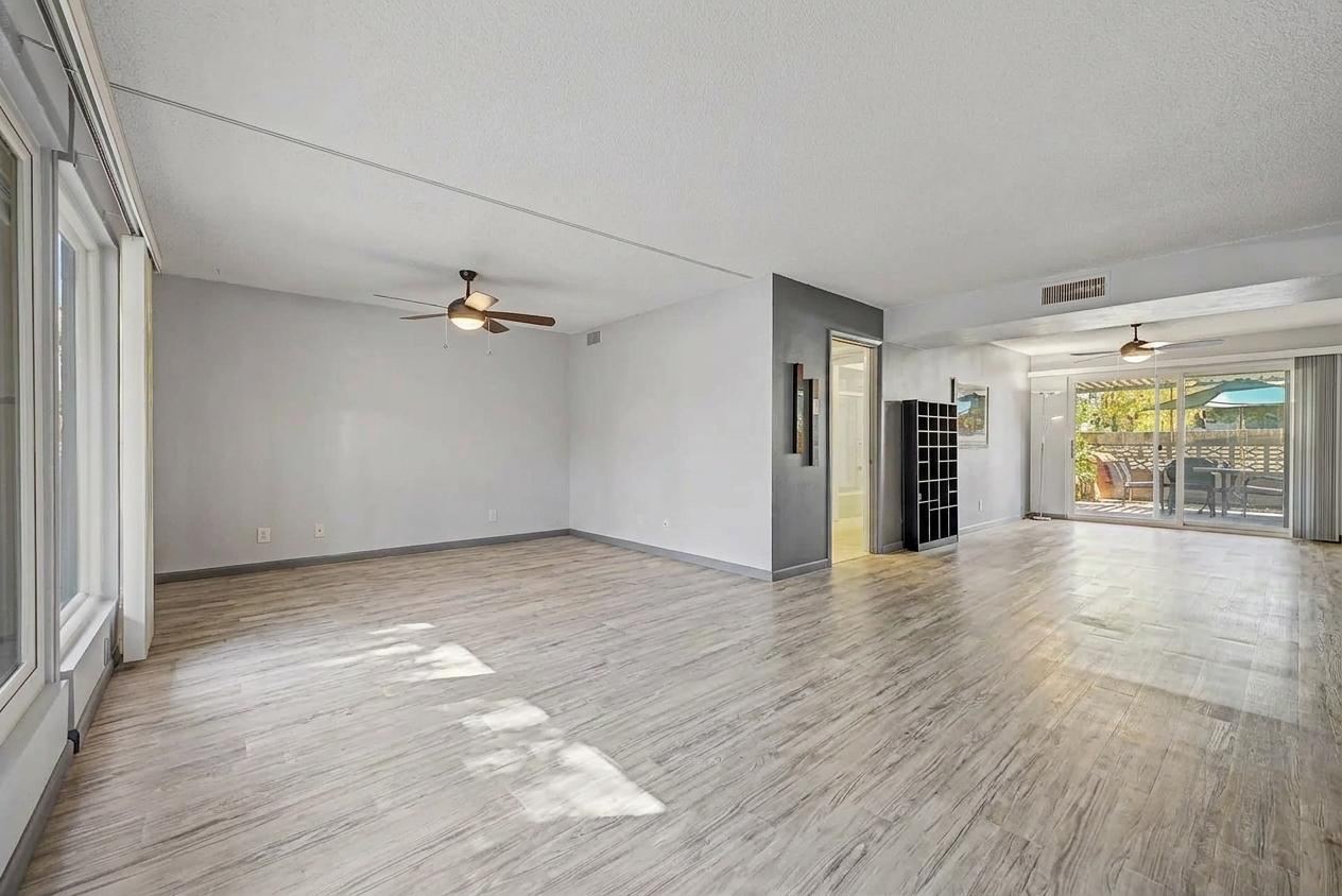 Open living and dining space with wood-look flooring and a sliding door to the private patio