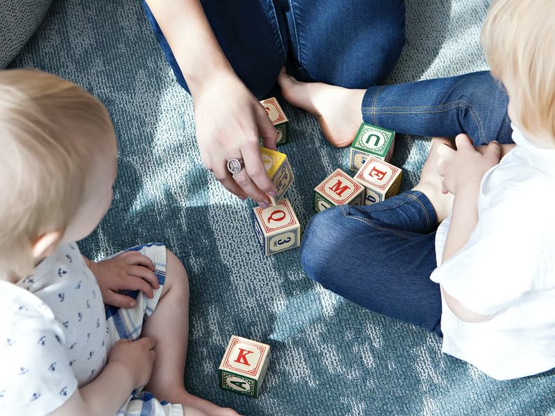 Young children playing with lettered blocks