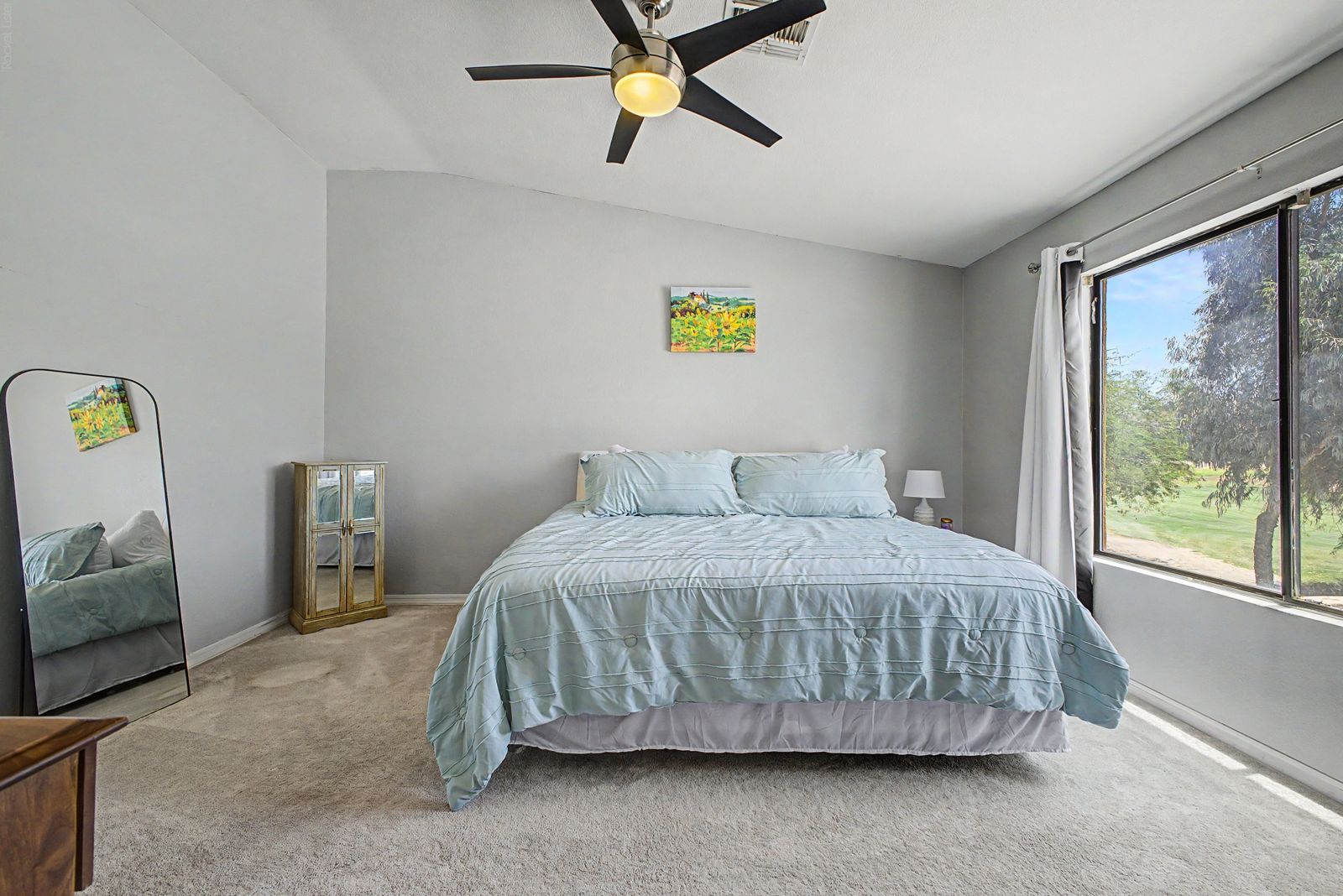 Primary bedroom with vaulted ceiling and green views