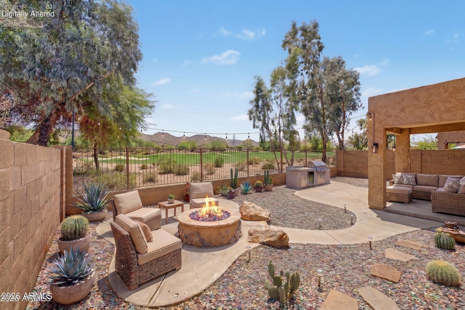 Digitally altered rendering of the backyard with a fire pit, outdoor kitchen, string lights and patio furniture added. These features are not currently on the property.